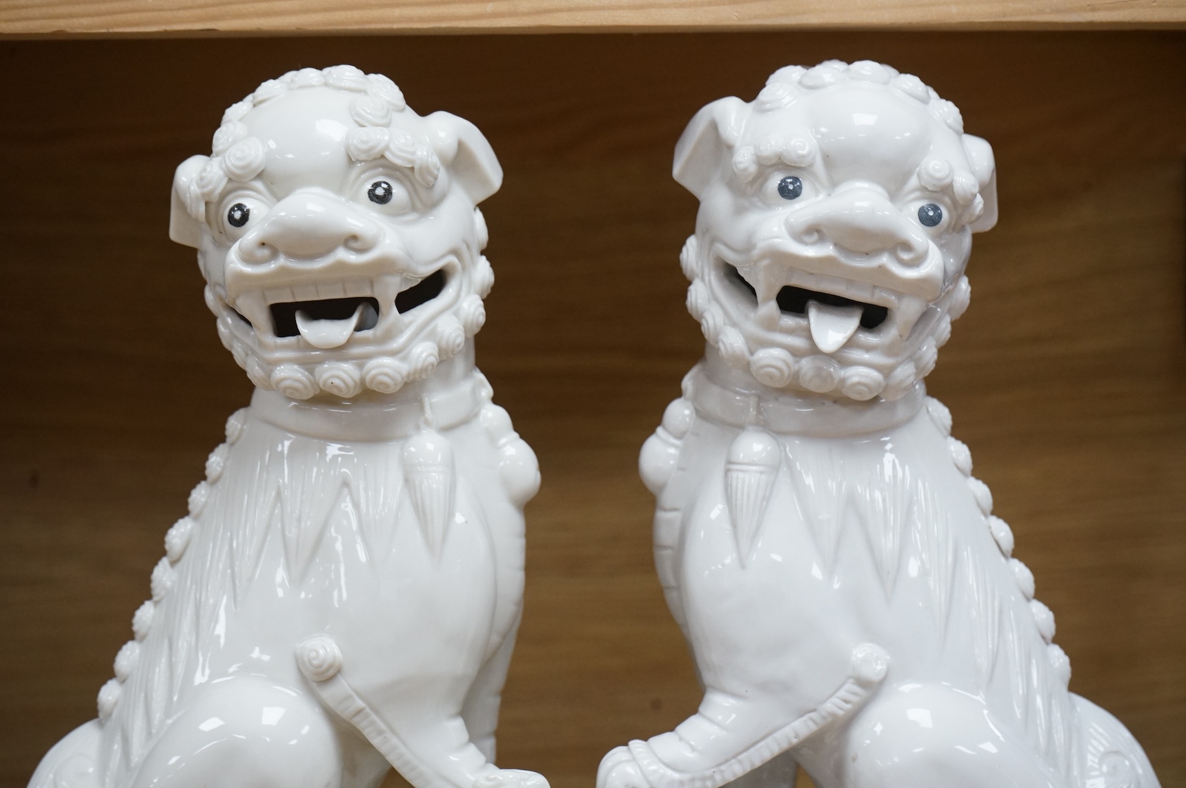 A pair of Chinese white glazed lion dogs, stamped ‘Wai Ming Hong Kong’ to base, 30cm